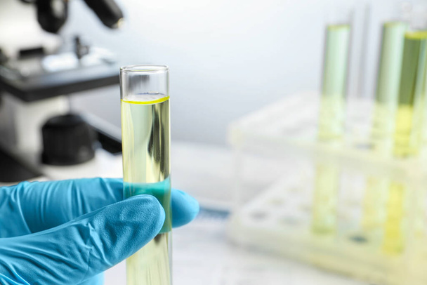 Doctor holding test tube with urine sample for analysis in laboratory, closeup. Space for text - Foto, Imagen