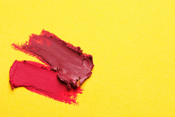Smears of bright lipsticks on yellow background, top view. Space for text - Zdjęcie, obraz