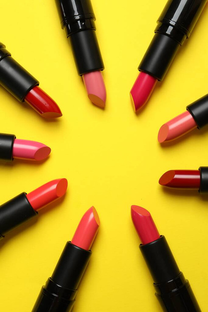 Frame of bright lipsticks on yellow background, flat lay. Space for text - 写真・画像