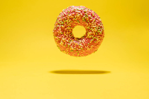 Левітаційний рожевий пончик на жовтому тлі. Творче харчування фону
 - Фото, зображення