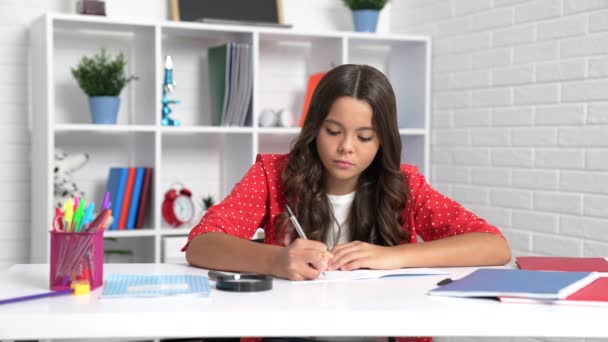 Chica seria niño escribir en copybook haciendo tarea en el escritorio de la escuela, niño. - Imágenes, Vídeo