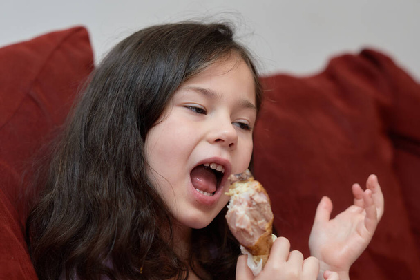 kifejező fiatal lány eszik csirke és zöldség vacsorára a kanapén, miközben TV-t néz - Fotó, kép