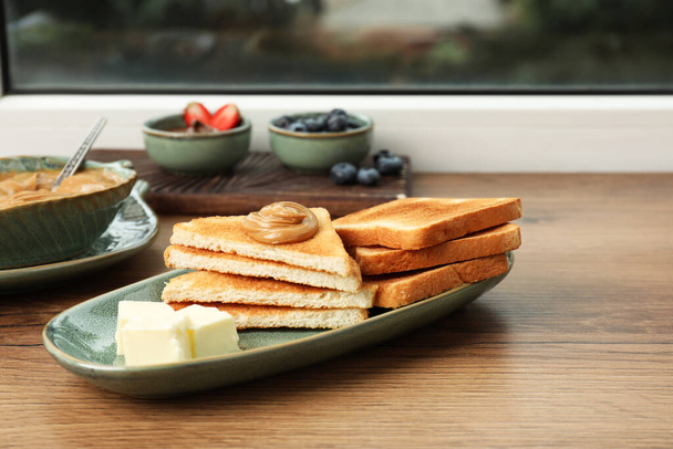 Tasty toasts and different toppings on wooden table at window - Φωτογραφία, εικόνα