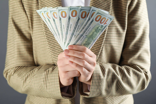 Woman holding banknotes on grey background, closeup. Money exchange concept - Φωτογραφία, εικόνα