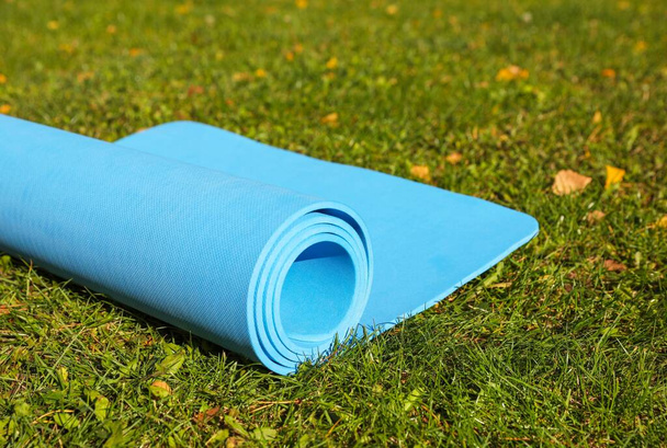 Blue karemat or fitness mat on fresh green grass outdoors, closeup - Foto, Imagen