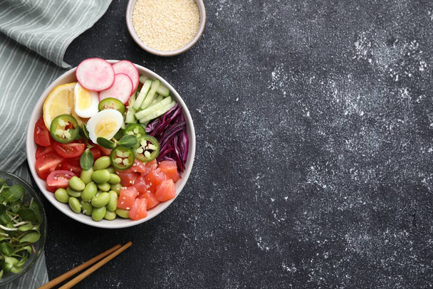 Poke bowl with salmon, edamame beans and vegetables on black table, flat lay. Space for text - Foto, Bild