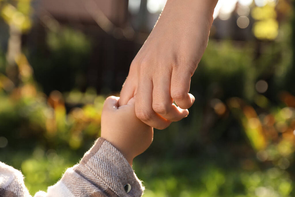 Daughter holding mother's hand outdoors, closeup view - Fotoğraf, Görsel