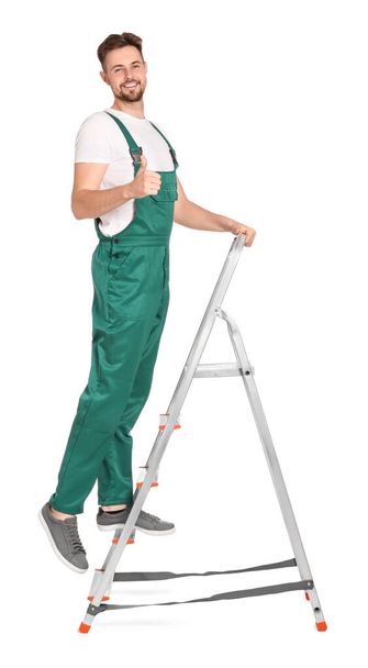 Worker in uniform climbing up metal ladder on white background - Photo, image