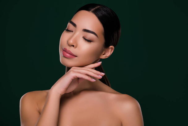 Portrait of charming lady touch her cheeks applying anti aging cream isolated on dark grey green color background. - 写真・画像