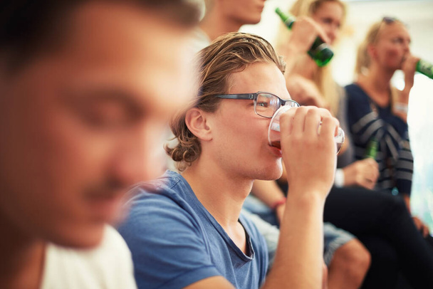 Taking a gulp of the good stuff. A young guy enjoying his drink at a music festival - Photo, Image