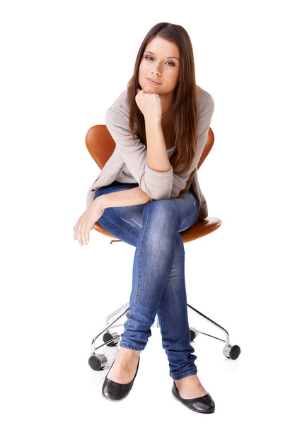 Shes got a thoughtful side. Studio shot of a beautiful young woman sitting on a chair against a white background - 写真・画像