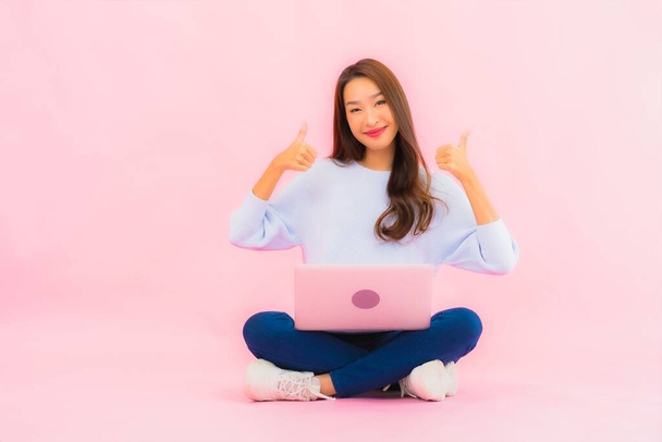 Portrait beautiful young asian woman use computer laptop on pink color isolated background - Foto, Bild