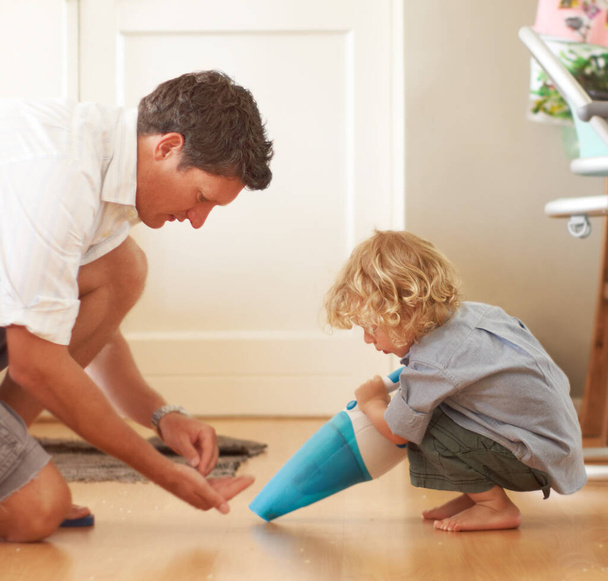 Дати батькові допомогу. Профіль батька на колінах перед сином і показує йому, як використовувати пилосос
 - Фото, зображення