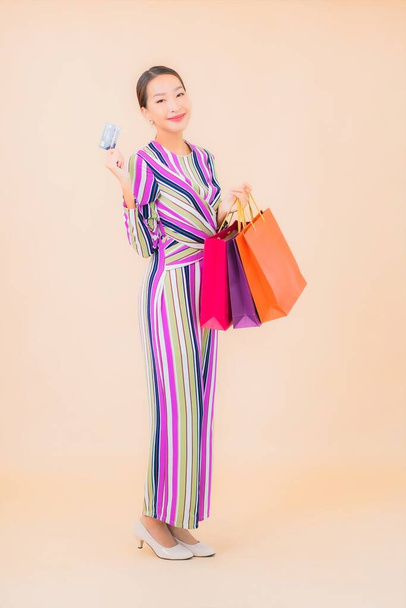 Portrait beautiful young asian woman with colorful shopping bag on color isolated background - Foto, imagen
