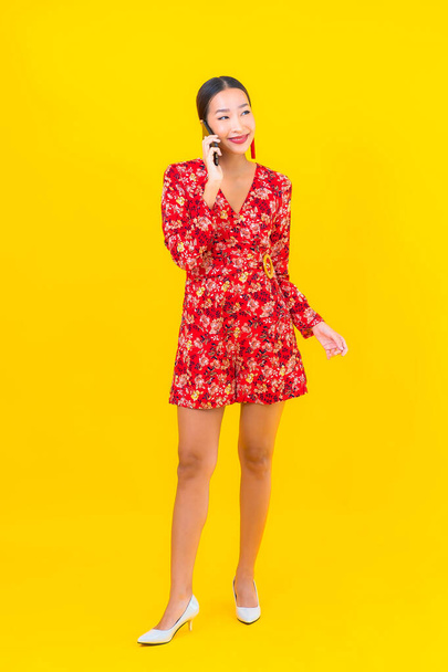 Porträt schöne junge asiatische Frau verwenden Smartphone auf gelbem Hintergrund - Foto, Bild