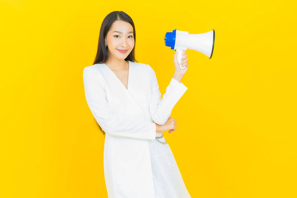 Ritratto bella giovane donna asiatica sorriso con megafono su sfondo di colore giallo - Foto, immagini