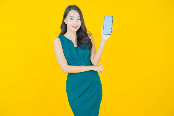 Portrait beautiful young asian woman smile with smart mobile phone on color background - Foto, Imagem