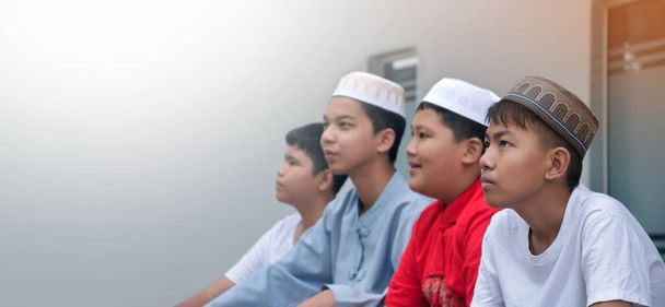 Asian muslim or islamic boys sitting with muslim boys in a row to pray or to do the religious activity, soft and selective focus. - Foto, immagini