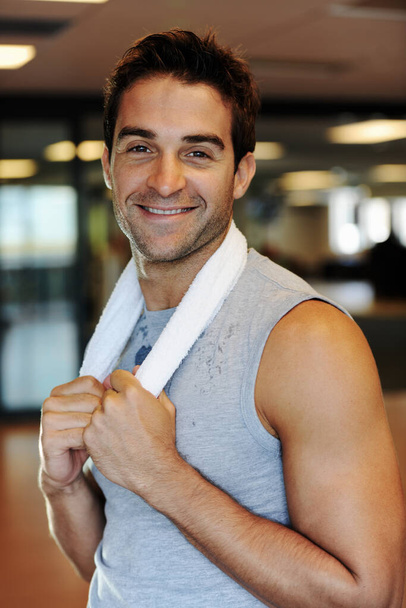 Hes gym visit was a great success. A smiling handsome man holding a towel around his neck A after a workout at the gym - Фото, зображення