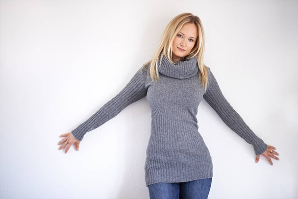 Showing off her winter style. Attractive young woman dressed in warm winter clothing posing against a grey background - Foto, Bild