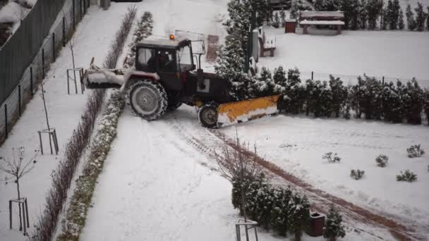 Traktor čistí sníh štětcem ve městě. - Záběry, video