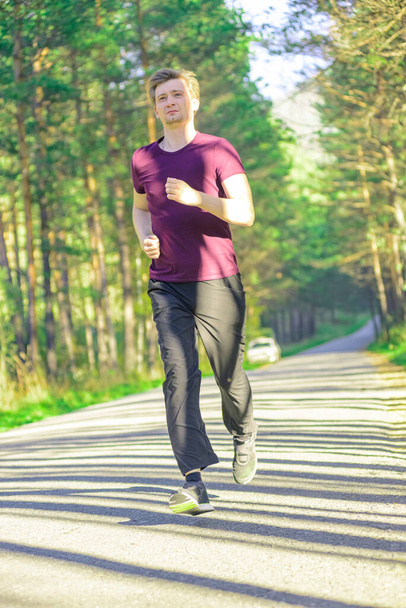 Running man joggen in het stadspark op mooie zomerdag. Sport fitness model Kaukasische etniciteit training outdoor. - Foto, afbeelding