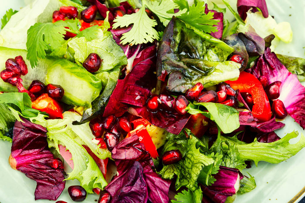 Vitamin salad with greens, bell pepper, lettuce and cucumber, decorated with pomegranate. - Photo, Image