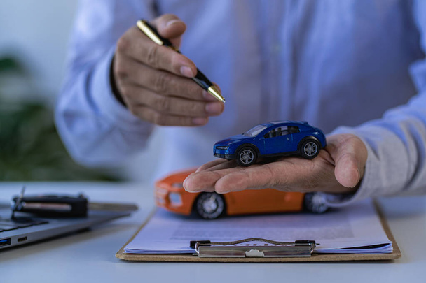 Selling a car. Management concept. The dealer gives the car keys to the new owner or renter with a contract of insurance. Customers who sign the contract and terms of the document agreement. - Фото, зображення
