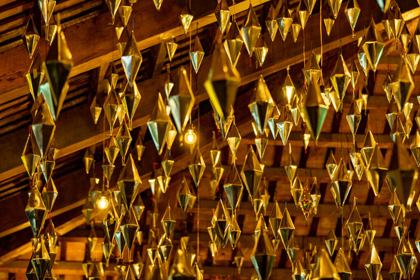 Diamantes o formas geométricas doradas colgando del techo de madera del porche granollers seguido como lámparas de luces - Foto, imagen