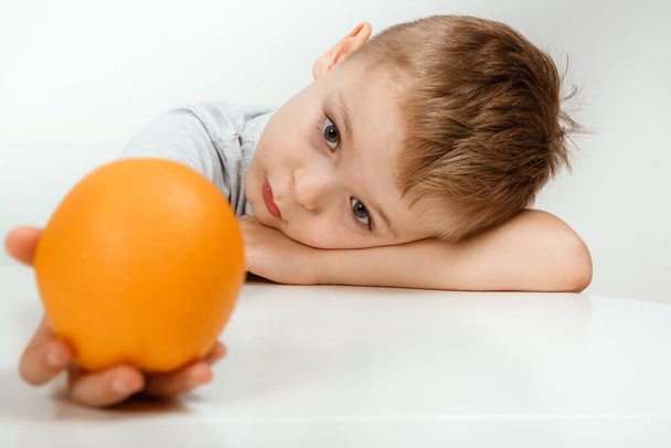 Garçon tenant des oranges isolées sur fond blanc. Le concept d'aliments sains pour bébés, vitamine C. Un endroit pour votre texte. - Photo, image