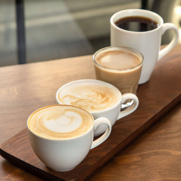 Diferentes tipos de café en tazas sobre fondo de madera, capuchino, americano, latte macchiato - Foto, imagen