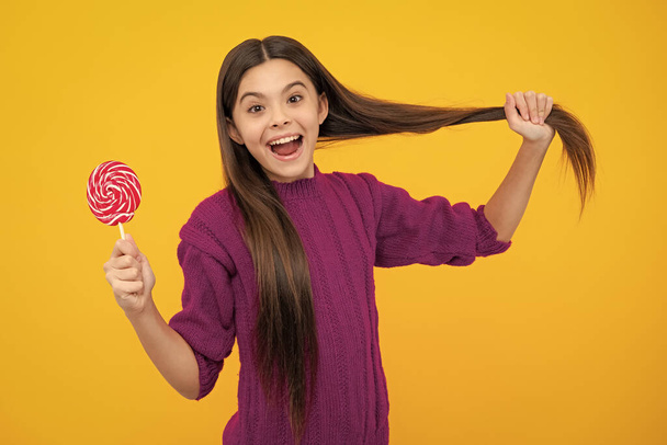 Excited face. Teenage girl with lollipop, child eating sugar lollipops, kids sweets candy shop. Amazed expression, cheerful and glad - Photo, Image