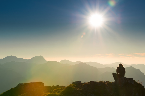 Eenzame triest persoon zit op de top van de berg bij zonsondergang - Foto, afbeelding