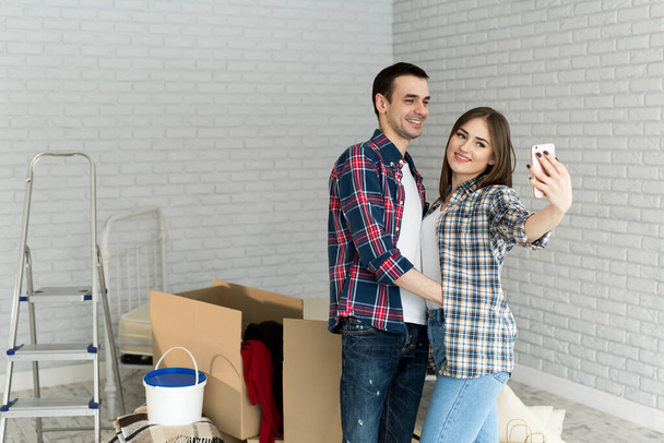 Young couple makes selfie while moving to a new apartment. Moving newlyweds to new housing - Foto, Bild