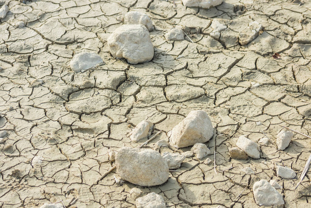 Risse im Boden eines ausgetrockneten Teichs mit weißen Steinen Klimawandel - Foto, Bild