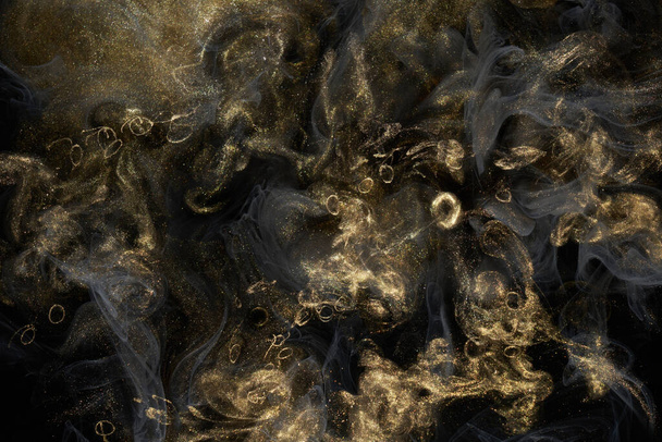 Golden sparkling abstract background, luxury black smoke, acrylic paint underwater explosion, cosmic swirling ink - Photo, image