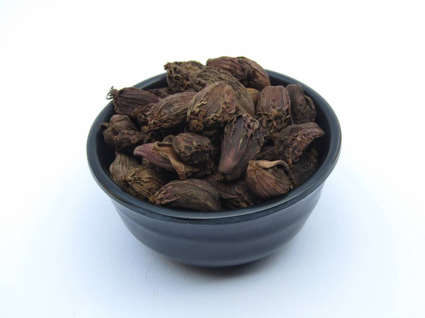 Black cardamom in a bowl on white background close-up view  - Photo, Image