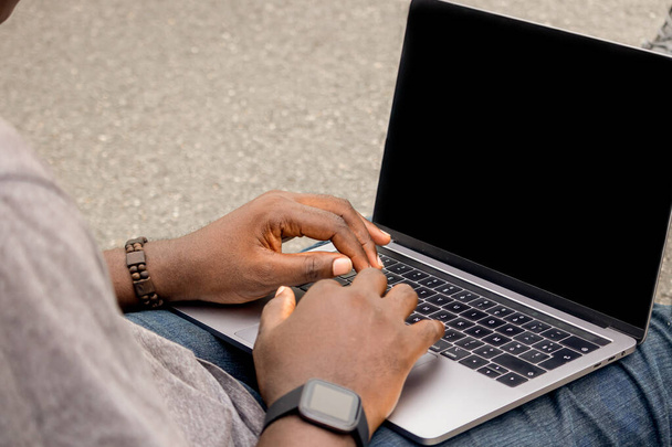 Χειροποίητο πορτραίτο αφρικανού προγραμματιστή που δουλεύει με το laptop του, με ένα smartwatch. - Φωτογραφία, εικόνα