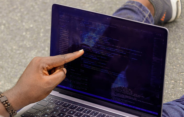 Handporträt eines afrikanischen Web-Entwicklers, der mit dem Finger auf Zeile des Computercodes zeigt - Foto, Bild