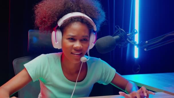 Young African American woman wearing headset play video game and live streaming online with microphone at home, gaming and esport or casting game, one person, broadcast and entertainment concept. - Footage, Video