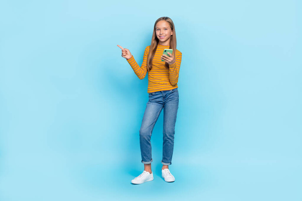 Full length portrait of positive cheerful girl hold telephone direct telephone empty space isolated on blue color background. - Φωτογραφία, εικόνα