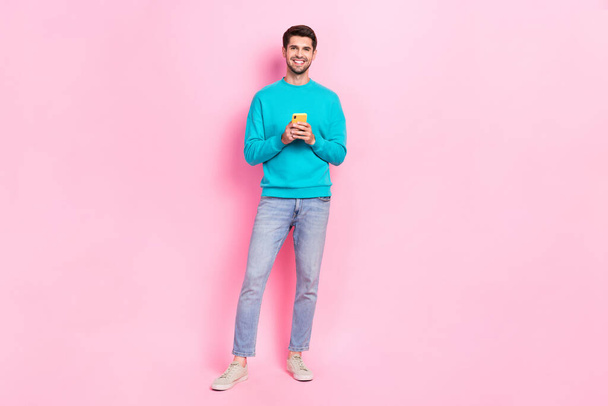 Full body photo of handsome young guy holding telephone email user subscribe wear trendy blue clothes isolated on pink color background. - Fotografie, Obrázek
