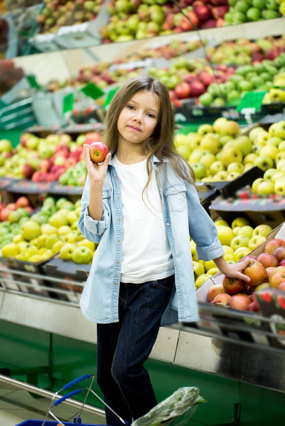 Little girl choosing a bio apple in a store - Фото, изображение