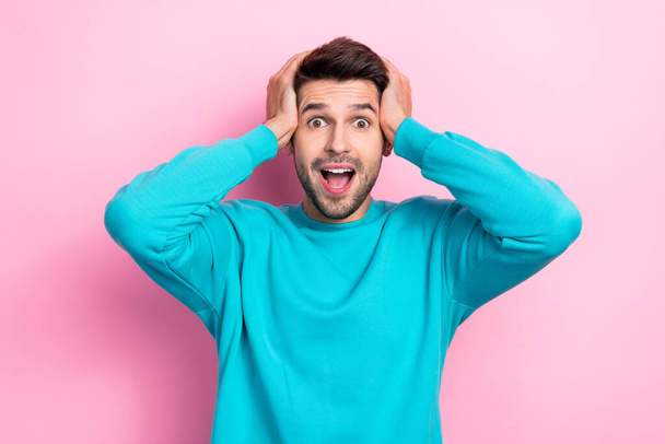 Photo of young crazy excited funny student man wear blue pullover touch hands head open mouth unexpected good news isolated on pink color background. - Zdjęcie, obraz