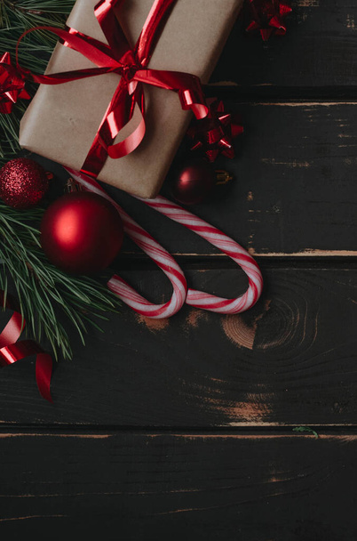 Vista superior foto Christmass flatlay caja de regalo, juguetes de árbol de Navidad rojo, piruletas y abeto brance sobre fondo de madera.Copiar sapce.Vertical foto. - Foto, imagen