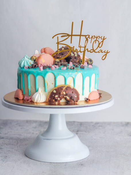 fánkok habcsók bogyók és csillogás tetején cukormázas csepegtető türkiz torta születésnapi ünneplés - Fotó, kép