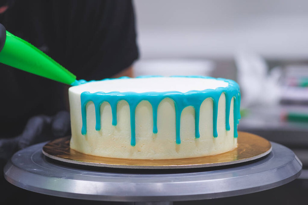 zak piping vulling topping op glazuur druppel turquoise taart voor verjaardag viering - Foto, afbeelding
