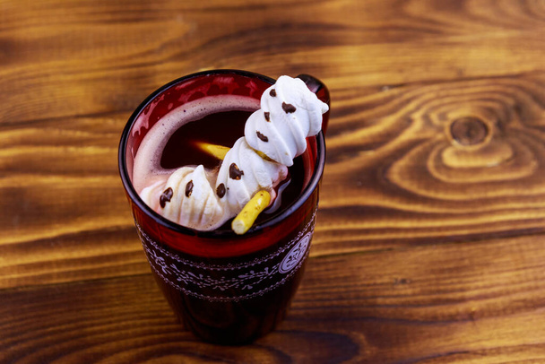 Melted marshmallow snowman in a cup of hot chocolate on wooden table - Fotó, kép