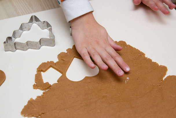 Kind schneidet Weihnachtslebkuchen aus Teig - Foto, Bild
