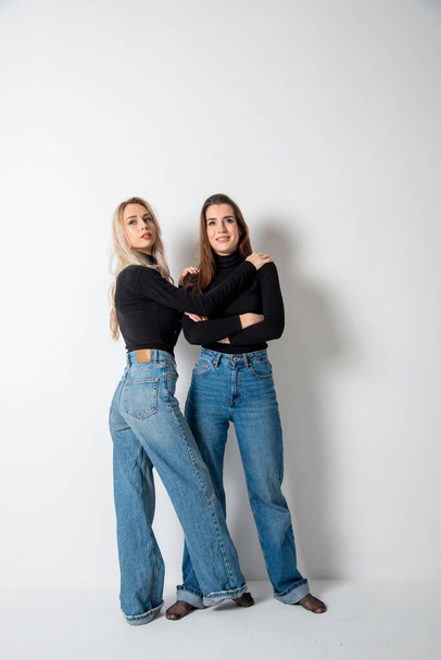 two beautiful girls brunette and blonde posing in studio against gray - Foto, Bild